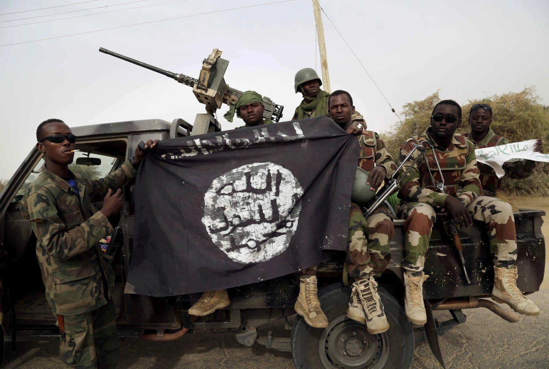 Nigerian soldiers hold up a Boko Haram flag that they had seized in the recently retaken town of Damasak, Nigeria. (REUTERS)
