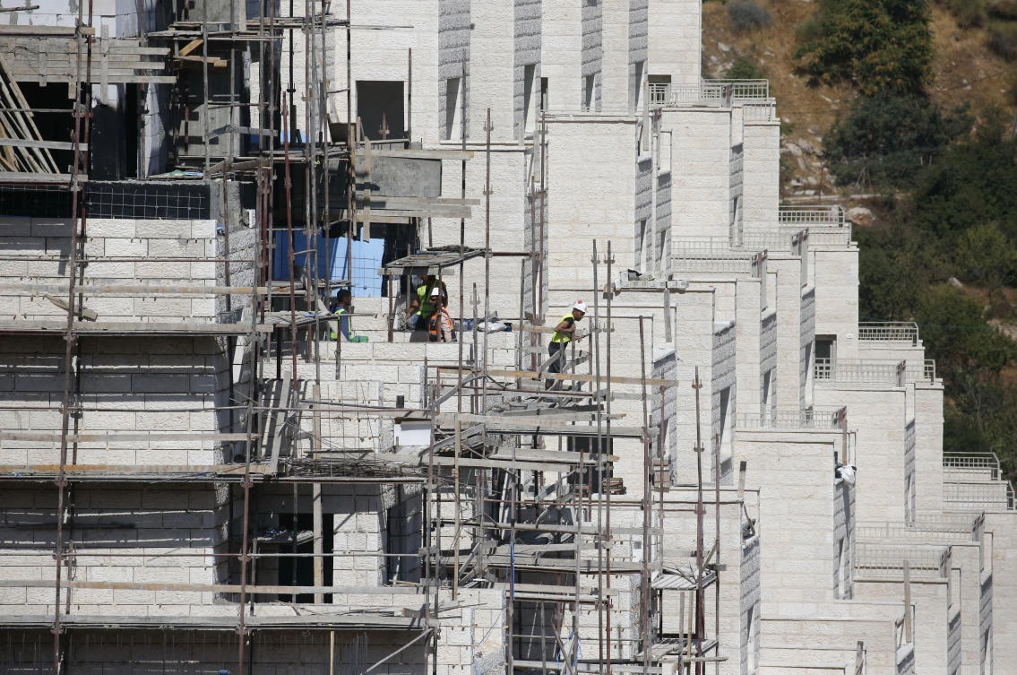 Construction workers build new houses in the Israeli settlement of Kiryat Arba, east the West Bank town of Hebron. (File photo: AFP)