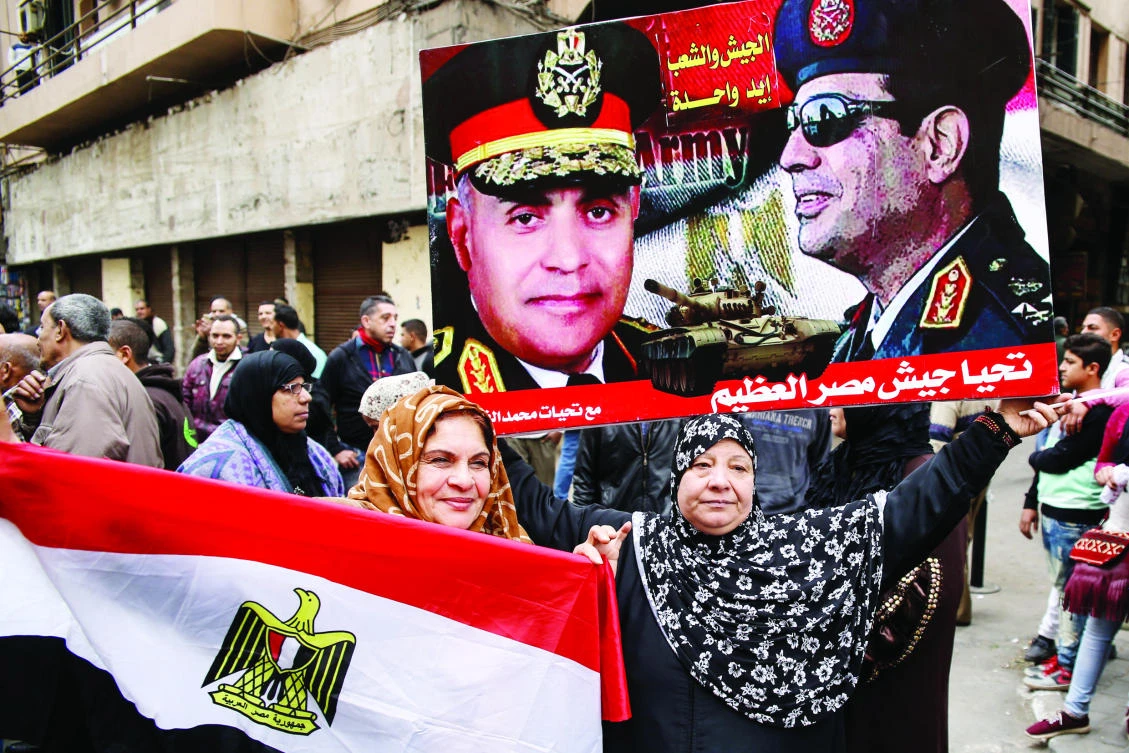 Egyptian women carrying flag and a poster of Presiden El-Sisi, right, and Defense Minister Sedki Sobhi, as they celebrate the sixth anniversary of the 2011 uprising. (Files/AFP)