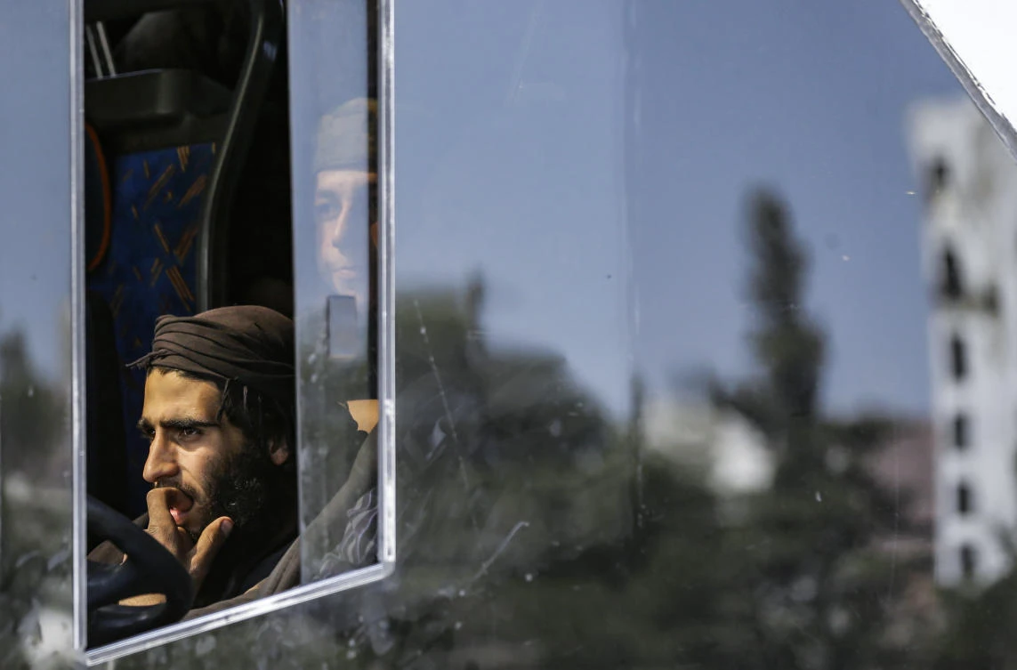 Syrian rebel fighters evacuated from Eastern Ghouta ride in a bus arriving at a government-held area at the entrance of Harasta on the outskirts of Damascus, on March 25, 2018. (Louai Beshara/AFP)