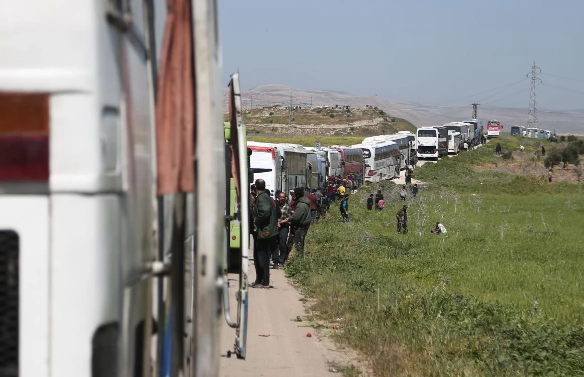 A convoy transporting Syrian civilians and rebel fighters evacuated from Eastern Ghouta waits in a government-held area prior to entering the village of Qalaat al-Madiq, some 45 kilometres northwest of the central city of Hama, on March 26, 2018. (AFP)