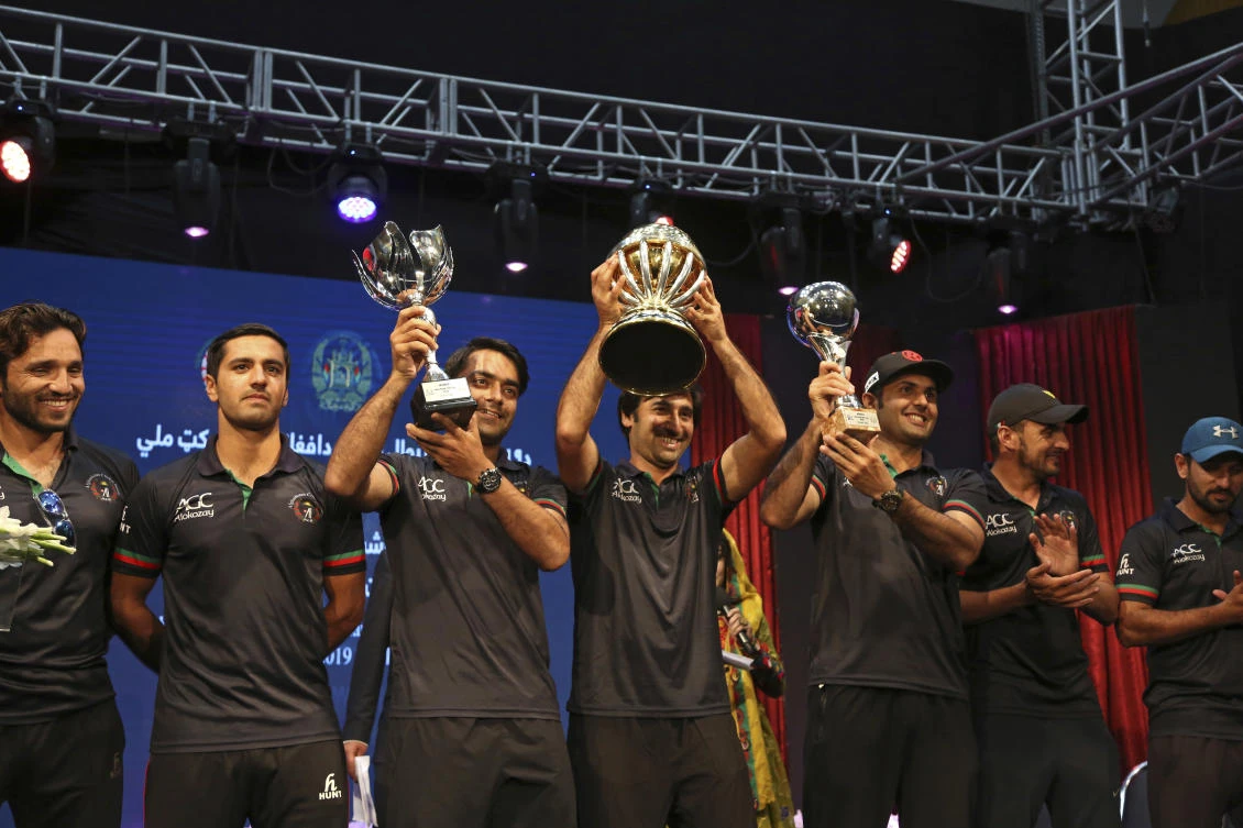 Afghanistan's cricket captain Asghar Stanikzai (C) holds the trophy they won after defeating West Indies in the 2019 World Cup qualification tournament on Sunday, as they celebrate, in Kabul. (AP)