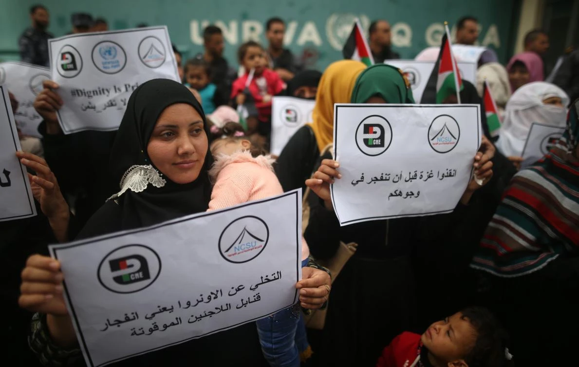 Palestinian women hold signs reading in Arabic (R to L) “Save Gaza before it explodes in your faces” and “Abandoning the UNRWA means the explosion of the refugee time bombs,” during a demonstration outside the United Nations Relief and Works Agency for Palestine Refugees in the Near East (UNRWA) headquarters in Gaza City on March 15, 2018. (AFP)