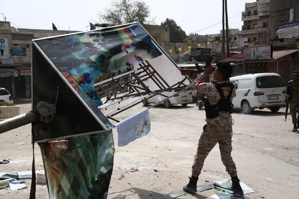 A Turkish-backed Syrian rebel destroys a poster of Kurdistan Worker's Party (PKK) leader Abdullah Ocalan in the city of Afrin in northern Syria on March 18, 2018. (AFP)