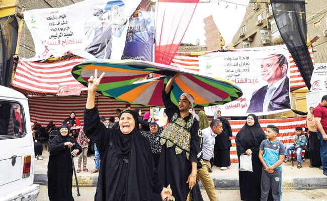 An Egyptian woman joins celebrations outside a polling station in Cairo’s western Giza district on Wednesday as the 2018 presidential poll entered its third and final day. (AFP)