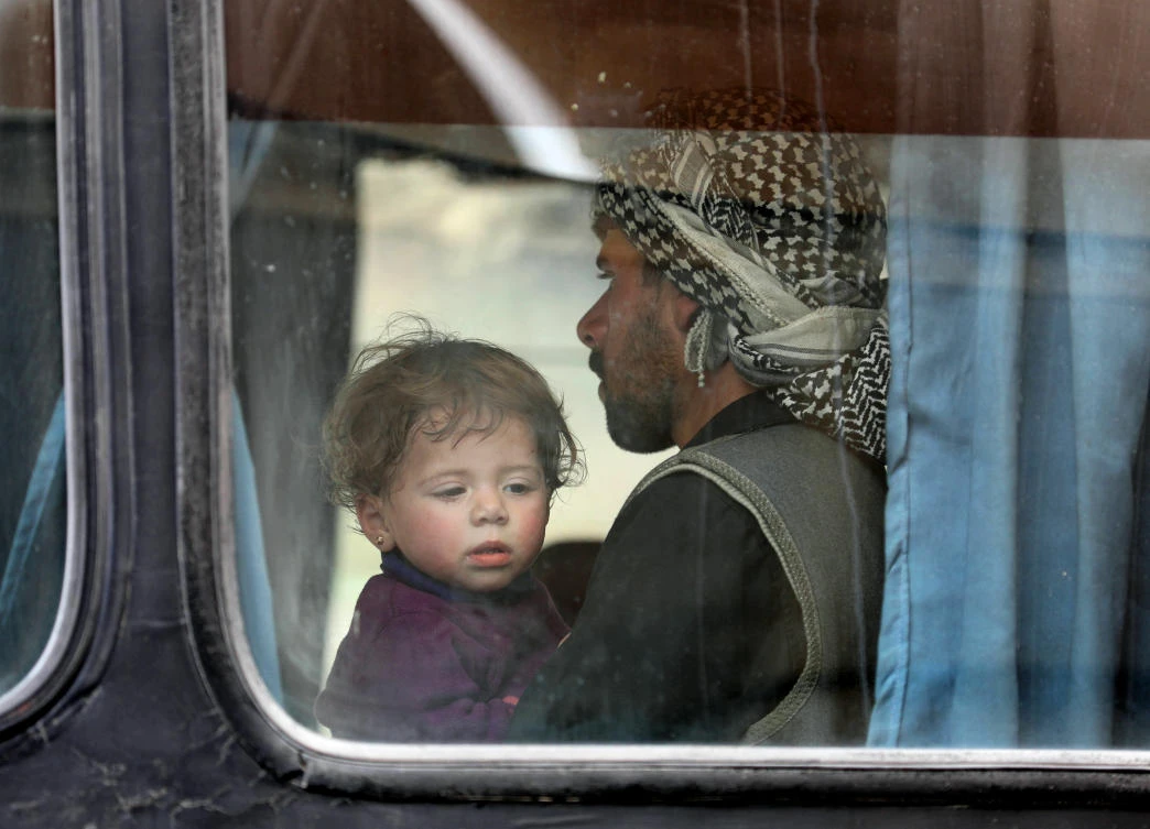 A child looks out of the window of a bus as Syrian civilians and rebels evacuated from the Eastern Ghouta region arrive in Qalaat Al-Madiq, some 45 kilometers northwest of the central city of Hama, on March 28, 2018, following an evacuation deal between the Islamist rebel faction Faylaq Al-Rahman, which controls a part of Ghouta, and Russia, an ally of the Syrian President. (Omar Hajj Kadour/AFP)
