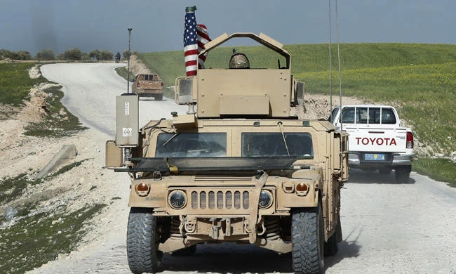 In this picture taken on March 29, 2018, a US military vehicle is seen on a road leading to the tense front line with Turkish-backed fighters, at Halawanji village, north of Manbij town, Syria. (AP Photo/Hussein Malla)