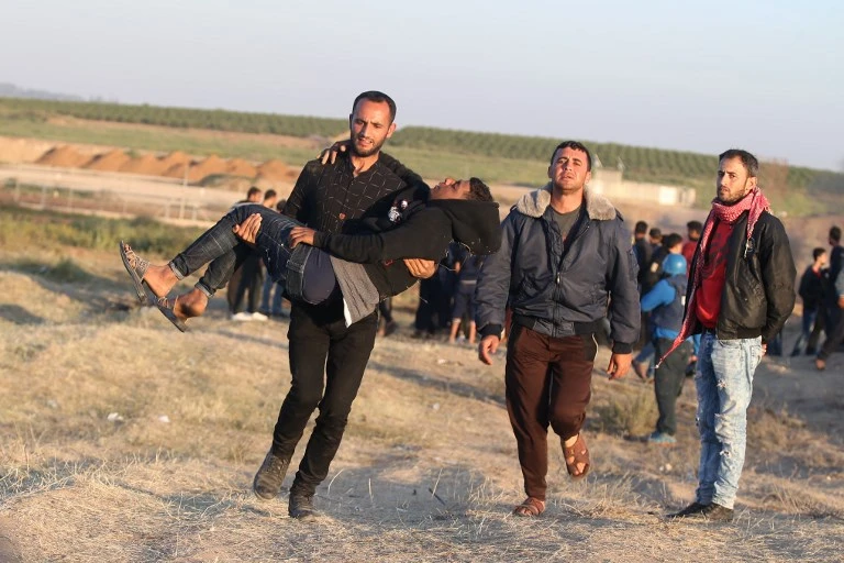 Palestinian protester carries an injured comrade during clashes with Israeli forces following a protest along the border with Israel, east of Gaza City on April 1, 2018. (AFP)