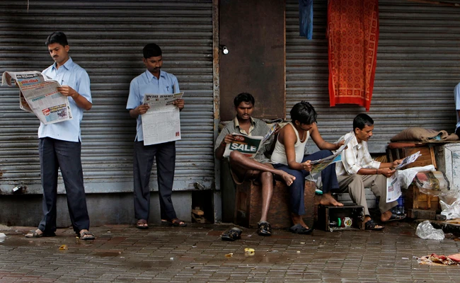 Indians read newspapers at Zaveri bazar, a market in Mumbai. India's Ministry of Information and Broadcasting has withdrawn a sweeping new order clamping down on journalists accused of spreading fake news. (AP Photo/Aijaz Rahi, File)