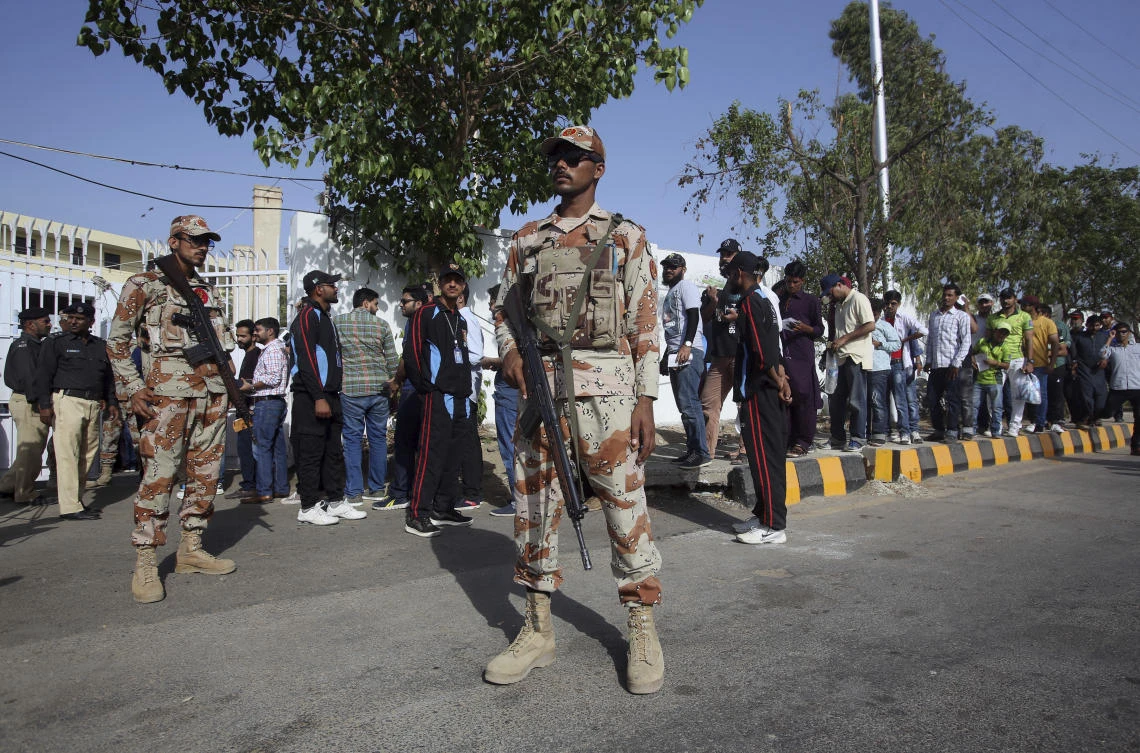 Pakistani paramilitary troops stand guard while cricket fans passing through a security checkpoint to enter the National Stadium for the Twenty20 match between Pakistan and West Indies in Karachi. (AP)