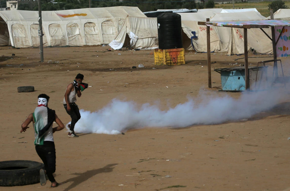 Palestinian demonstrators react to tear gas fired by Israeli troops during clashes at a tent city protest at the Israel-Gaza border, Apr. 5, 2018. (Reuters)