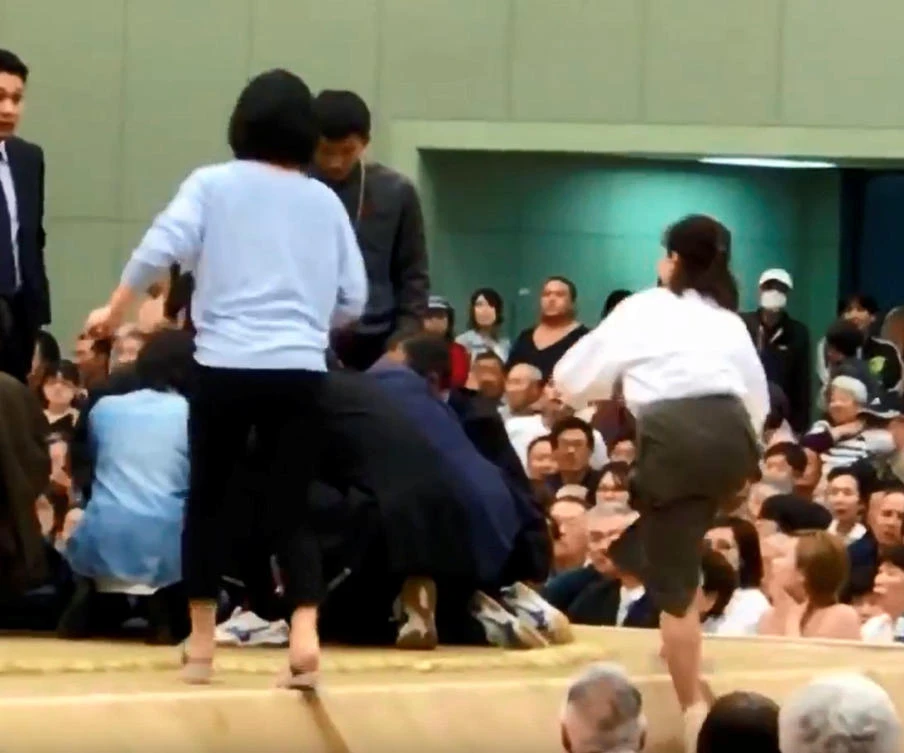 A photo grab from a Youtube video shows women climbing up a sumo ring to treat Maizuru city mayor Ryozo Tatami, who collapsed while making a speech in a gym in Maizuru, Kyoto prefecture, Japan April 4, 2018 in this photo released by Kyodo. (Kyodo/via Reuters)