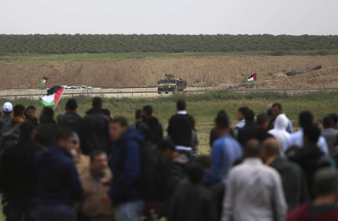 Protesters stand in front of Israeli soldiers during a demonstration near the Gaza Strip border with Israel, in eastern Gaza City. (AP)