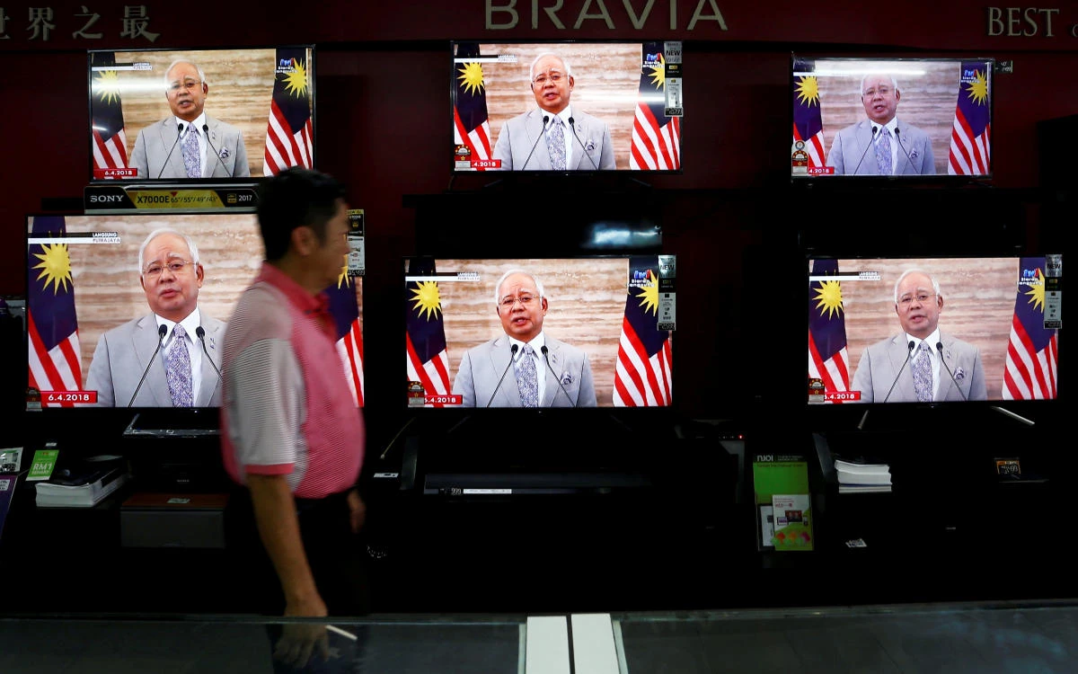 A man passes a live telecast of Malaysia’s Prime Minister Najib Razak as he addresses the nation on the dissolution of parliament on Friday, April 6. Najib said he met Malaysia’s king, Sultan Muhammad V, to gain approval for the dissolution. (Reuters)
