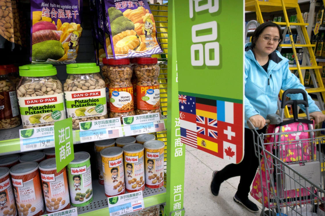 A woman pushes a shopping cart past a display of nuts imported from the United States at a supermarket in Beijing. (File Photo: AP)