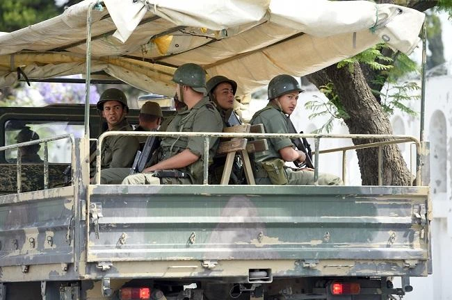 Tunisian soldiers sit on a truck as they monitor the area of the Bouchoucha army barrack. (AFP)