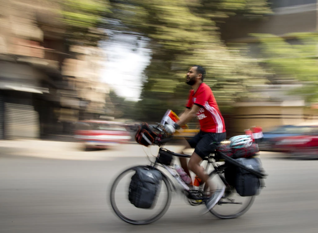 In this picture taken with low shutter speed, Mohammed Nufal, 24, rides his bicycle as he begins his long-haul journey to Russia in Cairo, Egypt, Saturday, April 7, 2018. (AP)