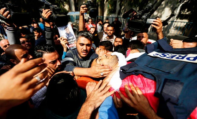 Mourners and journalists carry the body of Palestinian journalist Yasser Murtaja, during his funeral in Gaza City on April 7, 2018. (AFP)