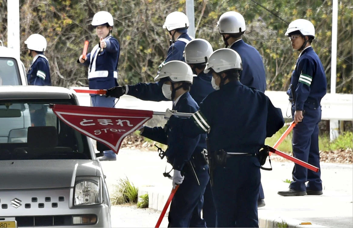 Police officers inspect cars at a checkpoint in Onomichi, Hiroshima prefecture in pursuit of a jail breaker. (AP)