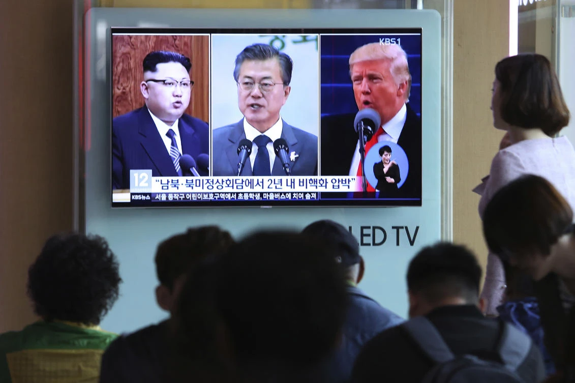 People watch a TV screen showing file footage of US President Donald Trump, right, South Korean President Moon Jae-in and North Korean leader Kim Jong Un, left, during a news program at the Seoul Railway Station in Seoul, South Korea, Wednesday, April 18, 2018. (AP/Ahn Young-joon)