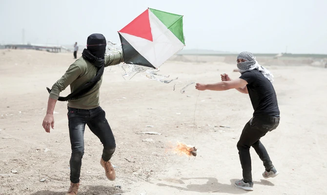 Palestinian protesters fly a kite with a burning rag dangling from its tail during a protest at the Gaza Strip's border with Israel, Friday. (AP)