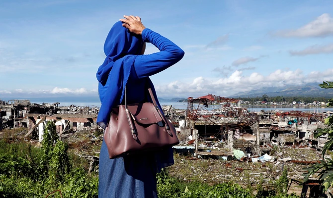 A woman looks at ruined houses, after residents were allowed to return for the first time to their homes on April 19, 2018, in Marawi, southern Philippines, since the battle between government troops and Daesh-inspired militants began in May 2017. (REUTERS/Erik De Castro)
