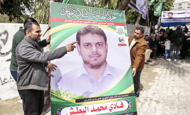 Men hold up a poster portrait of Fadi Mohammed Al-Batsh on Saturday outside his family’s house in Jabalia in the northern Gaza strip. (AFP)