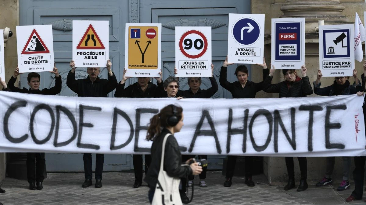 People hold placards and a banner reading “code of shame” during a demonstration organized by French organization to promote the rights of migrants and refugees “La Cimade,” outside the French National Assembly in Paris on April 16, 2018, to demand the withdrawal of the “asylum-immigration” law examined in parliamentary committee until April 19, 2018. (AFP/Stephane De Sakutin)