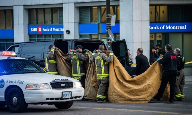 Officials carry a body into a vehicle after a van mounted a sidewalk crashing into pedestrians in Toronto on April 23, 2018. (Aaron Vincent Elkaim/The Canadian Press via AP)