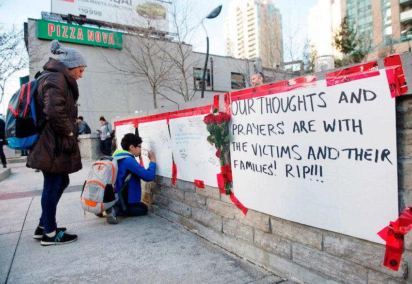 People sign a memorial after a driver plowed a rented van along a crowded sidewalk, killing multiple people and injuring others in Toronto. (The Canadian Press via AP)