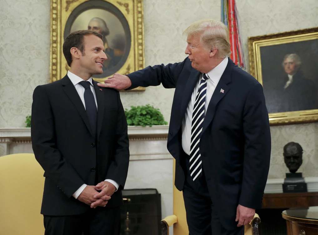 President Donald Trump playfully reaches over to cleans lint off French President Emmanuel Macron’s suit jacket during their meeting in Oval Office of the White House in Washington. (AP)