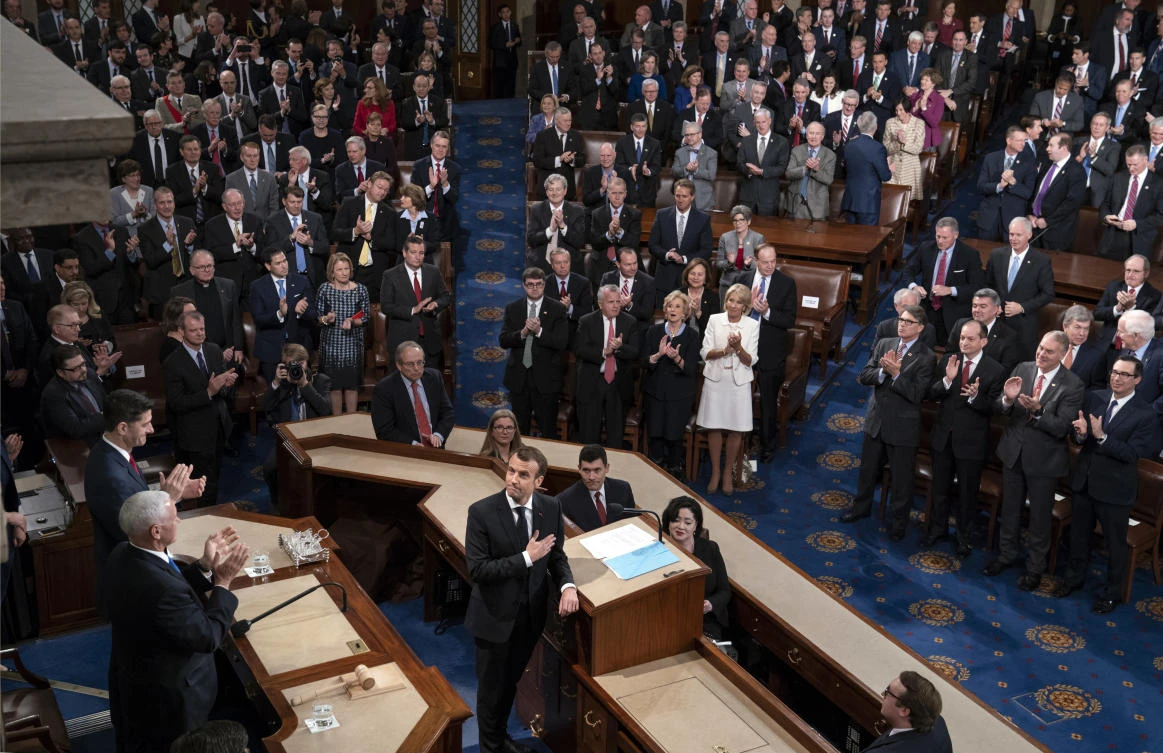 French President Emmanuel Macron touches his hand to his heart as he finishes his address to a joint meeting of Congress with Vice President Mike Pence and House Speaker Paul Ryan applauding at left, at the Capitol in Washington. (AP)