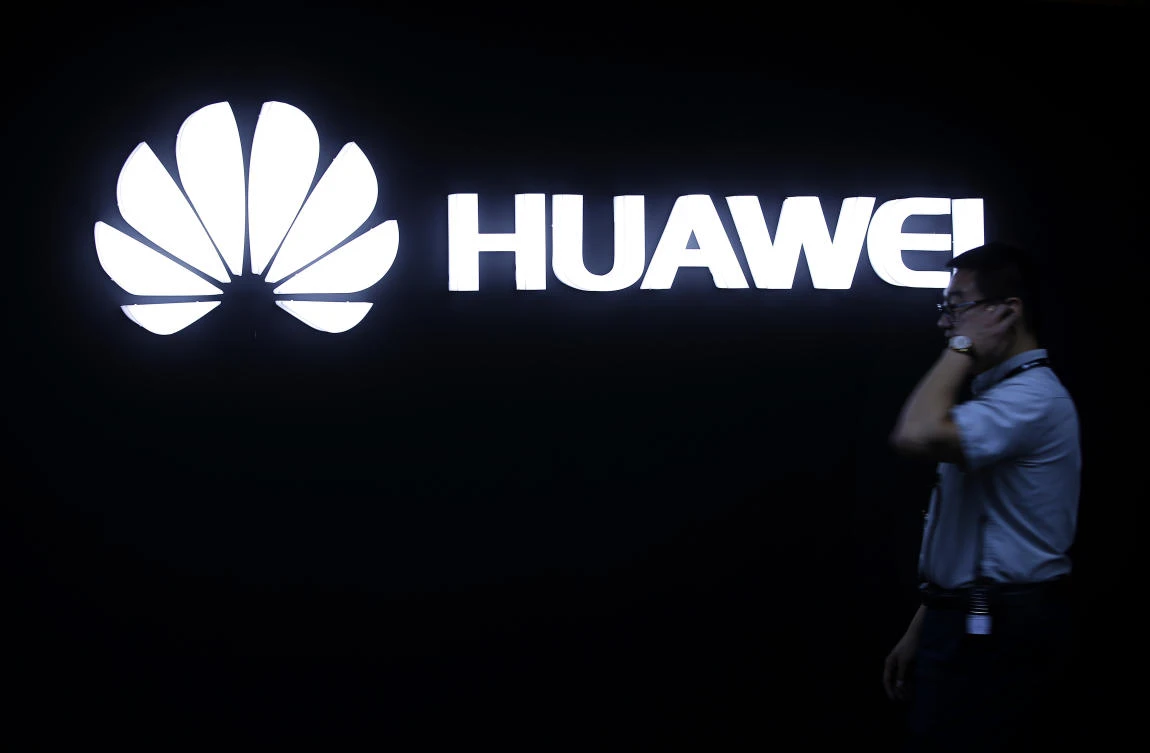 In this May 26, 2016, photo, a man walks past a Huawei logo during a launch event for the Huawei Matebook in Beijing. (AP/Mark Schiefelbein)