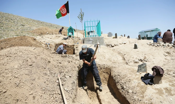 Afghan men prepare the graves for the victims of Sunday's suicide attack at a voter registration center in Kabul, Afghanistan,on April 23, 2018. (AP Photo/Rahmat Gul)