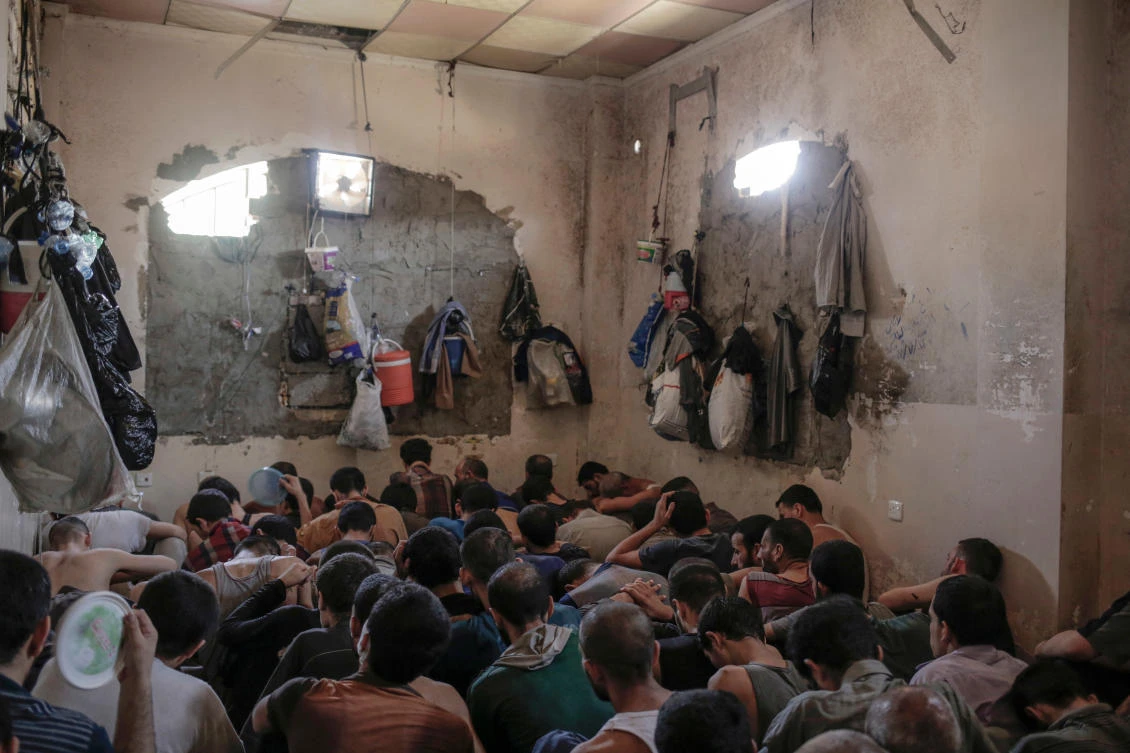 In this Tuesday, July 18, 2017 file photo, suspected Daesh members sit inside a small room in a prison south of Mosul. Iraq is holding huge numbers of detainees on suspicion of ties to the Daesh — around 11,000, according (AP Photo/Bram Janssen, File)