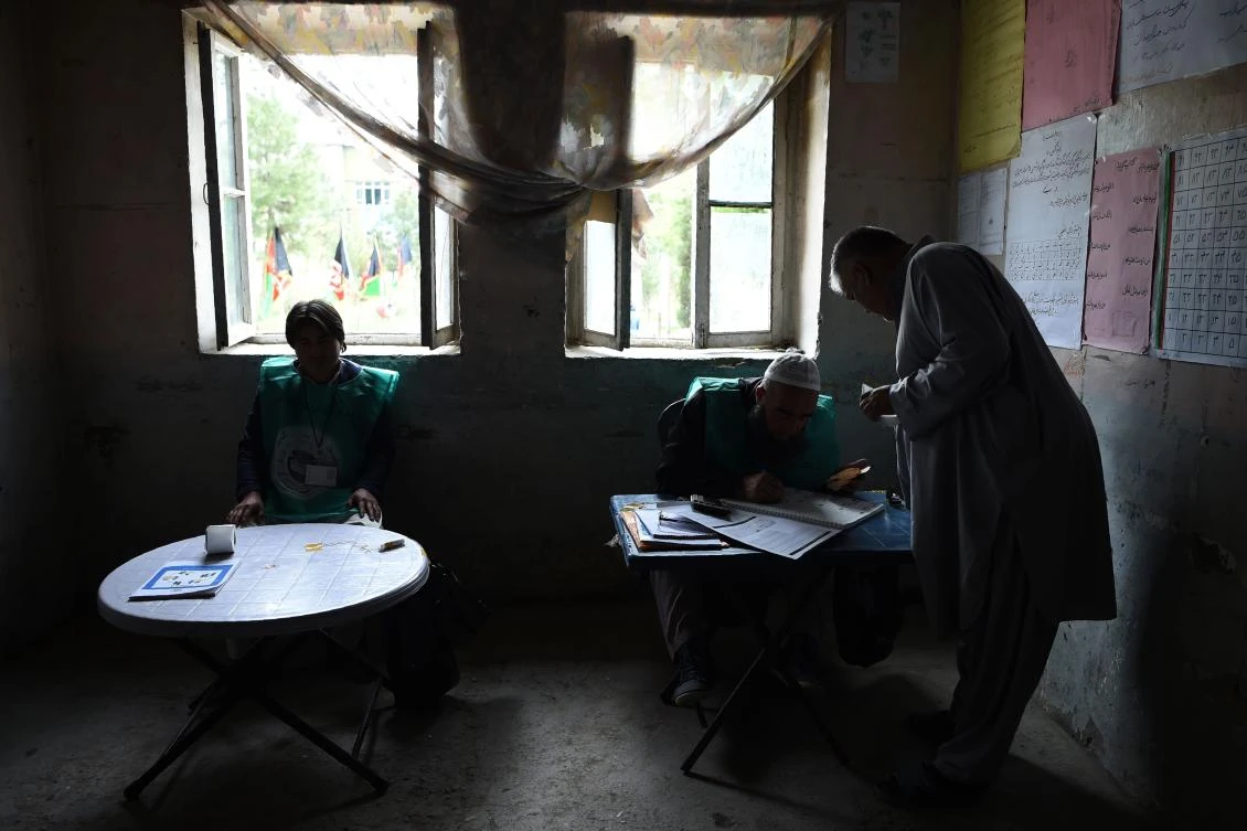 This photo taken on April 14, 2018 shows Afghan employees of the Independent Election Commission (IEC) registering a resident at a voter registration center for the upcoming parliamentary and district council elections in Kabul. (AFP/Wakil Kohsar)