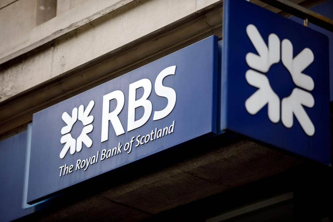 (FILES) In this file photo taken on October 22, 2017, signage is seen at the front of a branch of the Royal Bank of Scotland in central London on October 22, 2017. Britain's state-rescued Royal Bank of Scotland saw first-quarter net profits more than triple on lower restructuring costs and rising income, it said April 27, 2018. / AFP / Tolga Akmen