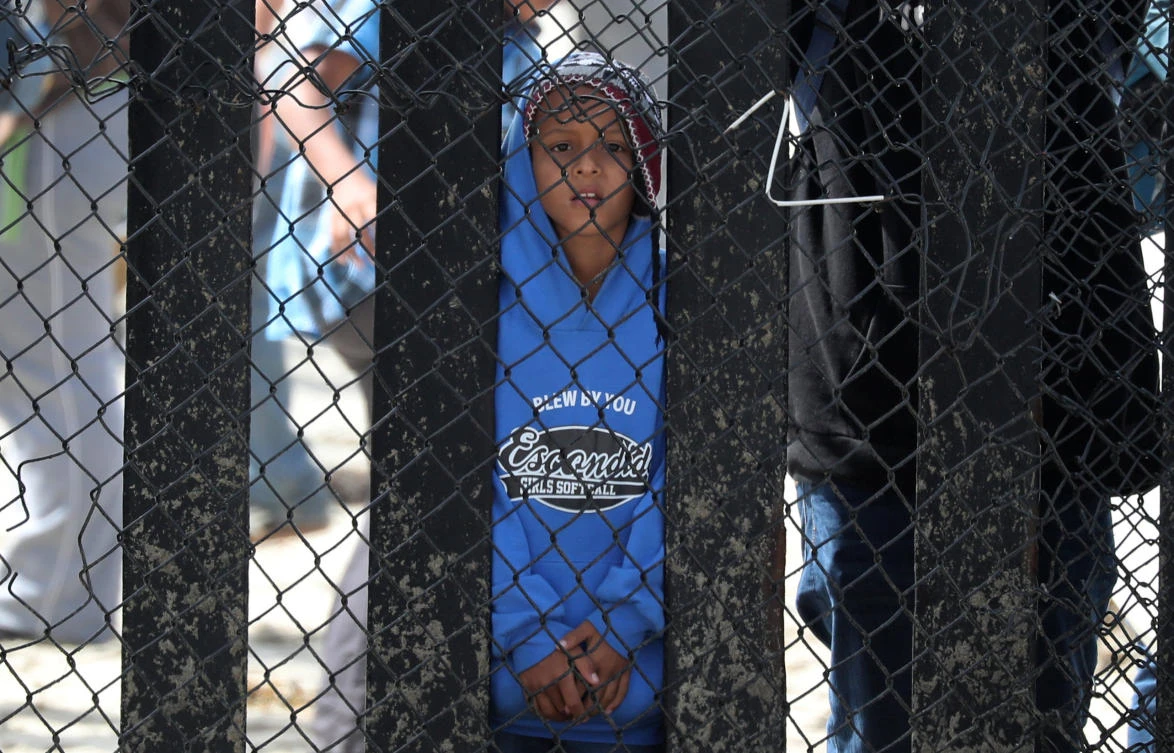 A boy who is with a migrant caravan from Central America look through the US-Mexico border wall at Border Field State Park before making an asylum request in San Diego. (Reuters)