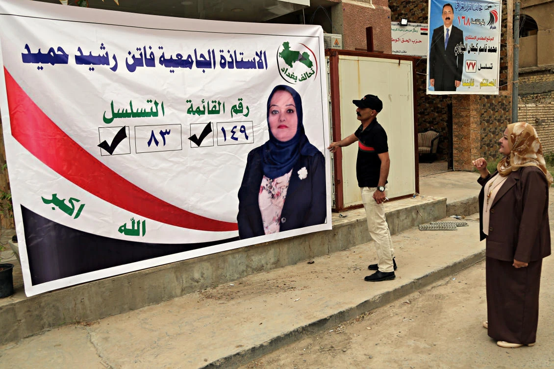 In this Saturday, April 21, 2018 photo, Ahmed Rashid places a campaign posters for his sister, Faten Rashid, a candidate for parliament, in Baghdad, Iraq. (AP)1