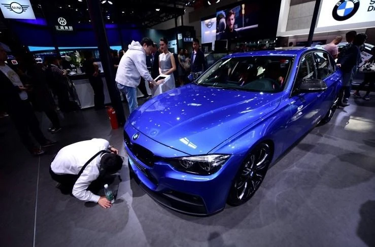 Net profit at the Munich-based group added 1.2 percent year-on-year to reach €2.3 billion. Above, visitors look at a BMW 330 Li on display at the Beijing auto show on April 25. (AFP)