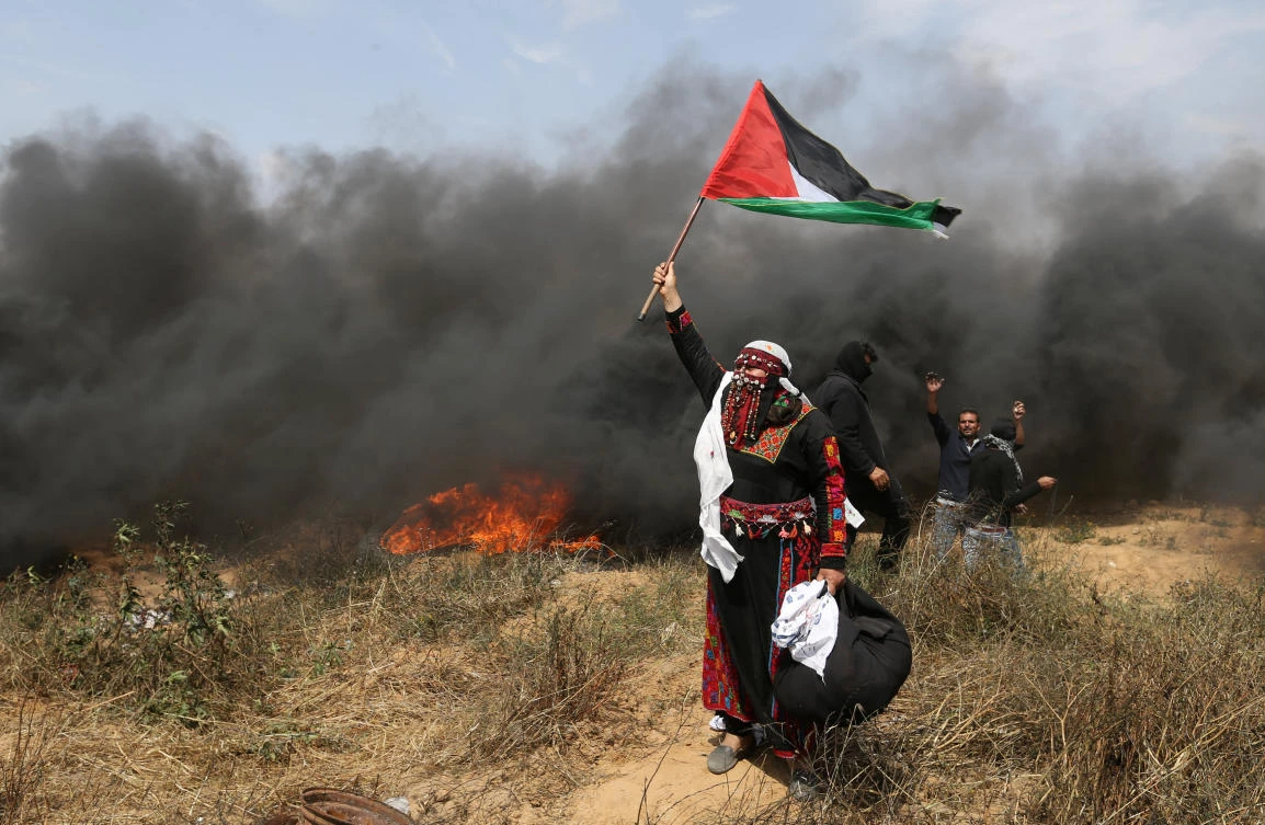 A woman demonstrator holds a Palestinian flag during clashes with Israeli troops during a protest at the Israel-Gaza border in the southern Gaza Strip. (Reuters)