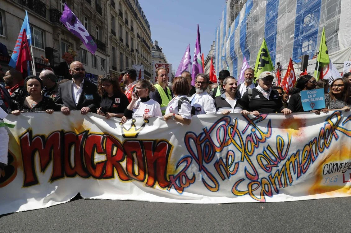 Protesters hold a banner which translates as "Macron, the party is only beginning" in central Paris, on May 5, 2018 during "The party for Macron" (La Fete a Macron) rally called to protest against the policies of the French president on the first anniversary of his election. (AFP)