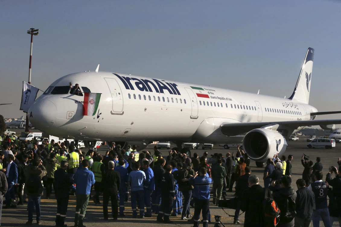 The pilot of Iran Air’s new Airbus plane waves a national flag after landing at Mehrabad International Airport in Tehran, Iran. From brand-new airplanes to oilfields, billions of dollars of deals stand on the line for international corporations as President Donald Trump weighs whether to pull America out of Iran’s nuclear deal with world powers. (AP/Vahid Salemi)