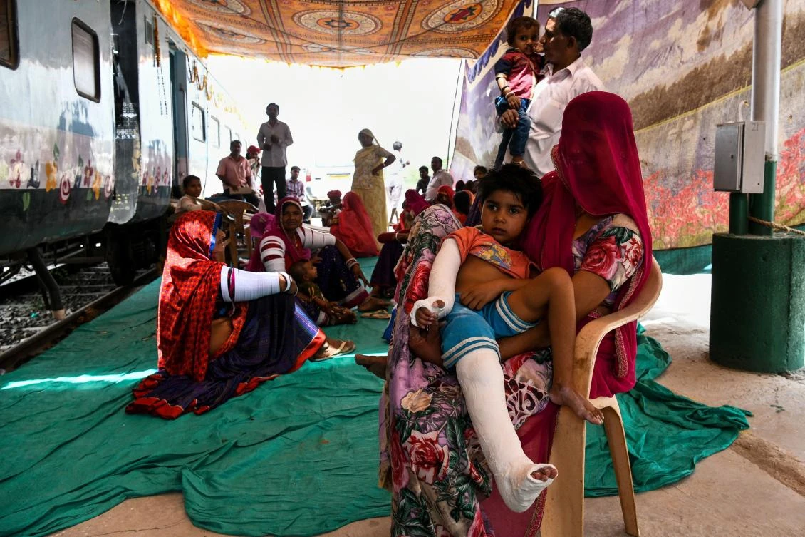 Patients and their relatives sit outside the train ahead of treatment on the Lifeline Express at a railway station in Jalore in India's western state of Rajasthan. (AFP)