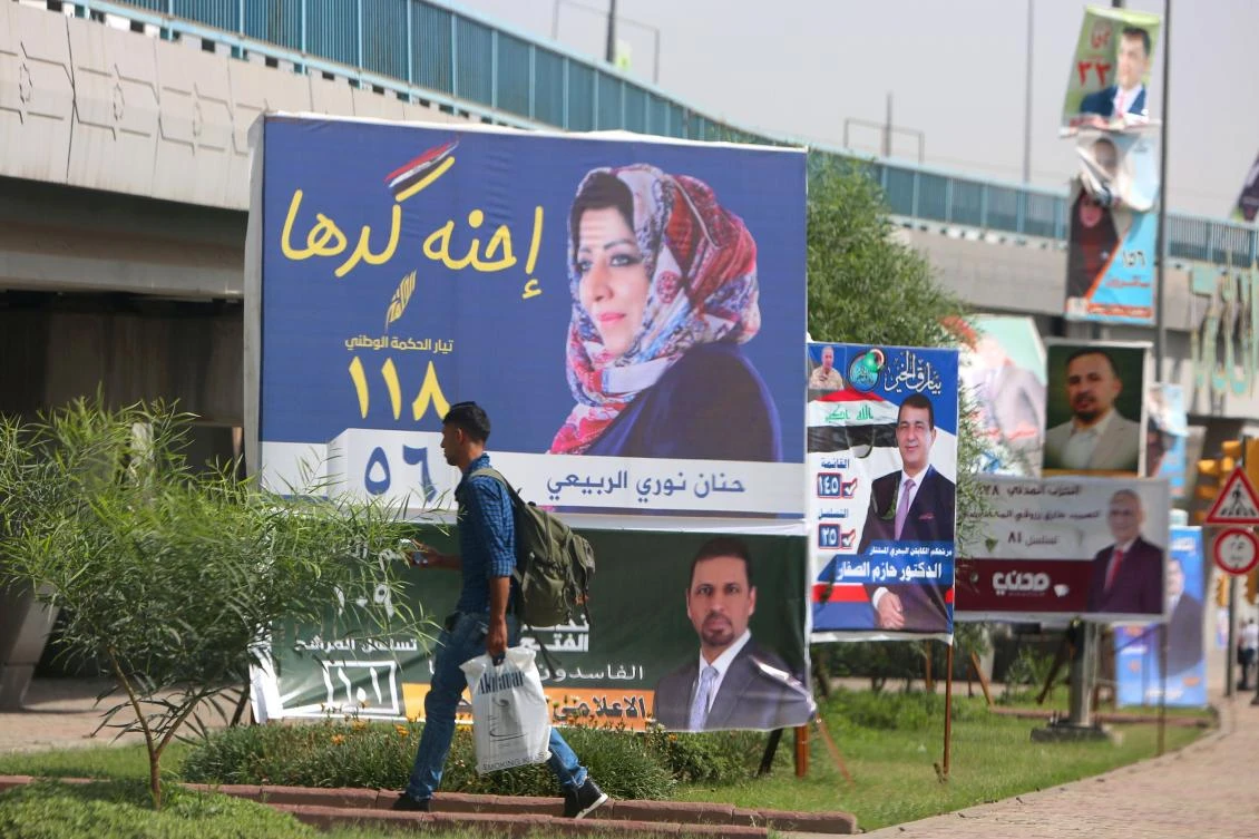 A man walks past electoral campaign posters in Baghdad on May 8, 2018. Arabic slogan on Hanan Nouri al-Rubaye's billboard (C) reads: "We are up to it". With campaign posters cluttering the streets of Iraq, the almost 7,000 candidates running for parliament in upcoming elections are resorting to increasingly wacky pitches to woo voters. / AFP / SABAH ARAR