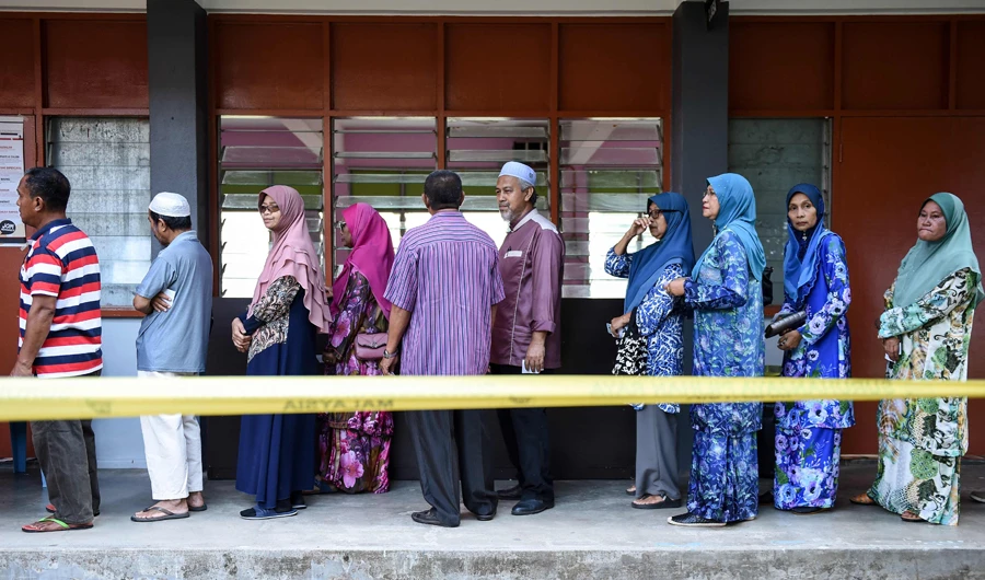 People queue outside a polling station during the 14th general elections in Pekan in Malaysia on May 9, 2018. (AFP)