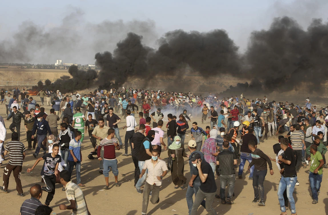 Palestinian protesters run for cover from teargas fired by Israeli troops during a protest at the Gaza Strip’s border with Israel, Friday, May 11, 2018. (AP)