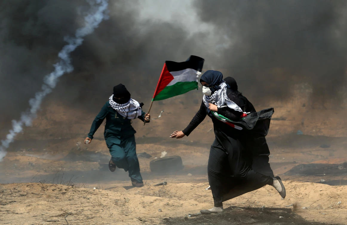 Female demonstrators run for cover from tear gas fired by Israeli forces during a protest where Palestinians demand the right to return to their homeland, at the Israel-Gaza border in the southern Gaza Strip. (Reuters)