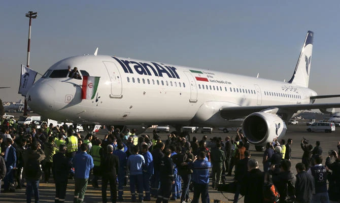 In this Jan. 12, 2017 file photo, the pilot of Iran Air's new Airbus plane waves a national flag after landing at Mehrabad International Airport in Tehran. European governments are scrambling for ways to save billions of dollars in trade that could collapse because of US President Donald Trump's decision this week to re-impose sanctions. (AP Photo/Vahid Salemi, File)