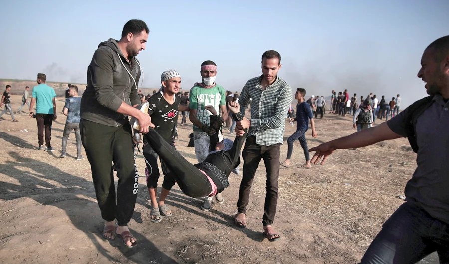 Palestinian protesters carry a wounded woman during a protest at the Gaza Strip's border with Israel, Tuesday, on May 15, 2018. (AP)